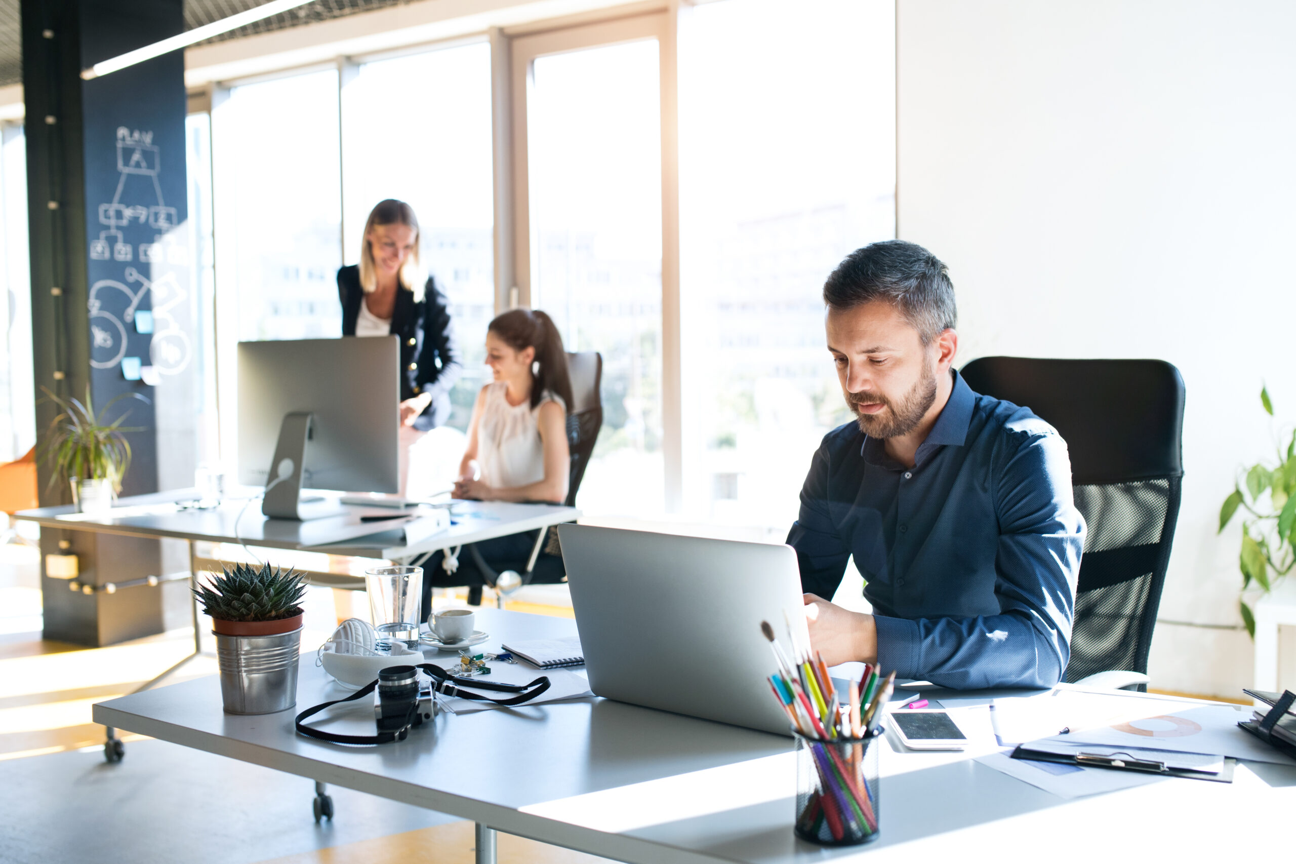 Three Business People In The Office Working Together.