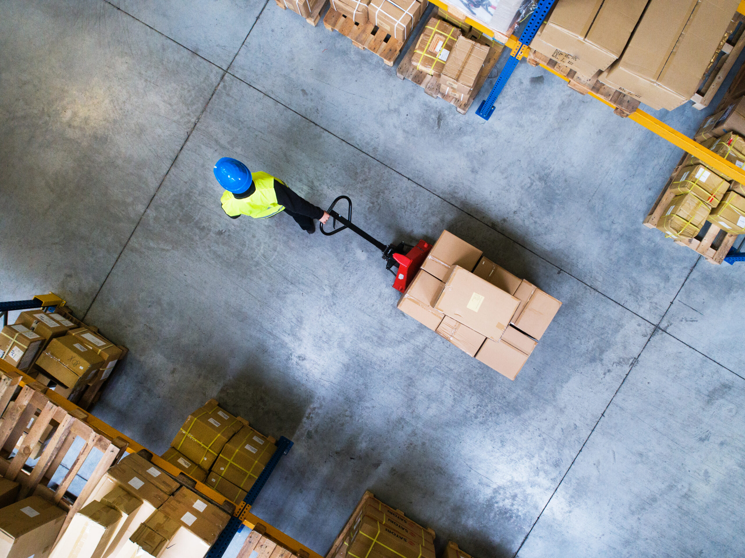 Male Warehouse Worker Pulling A Pallet Truck.