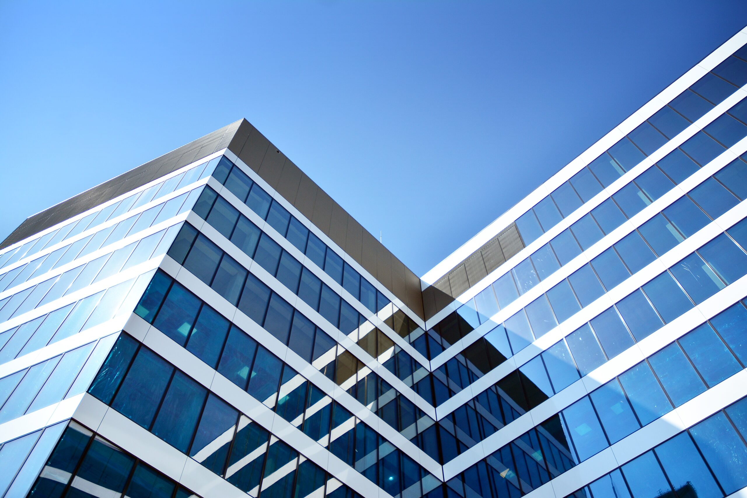 New Office Building In Business Center. Wall Made Of Steel And Glass With Blue Sky.